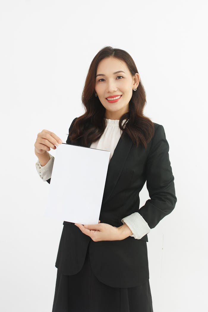 services-03 Smiling businesswoman in suit holding a blank document with copy space.