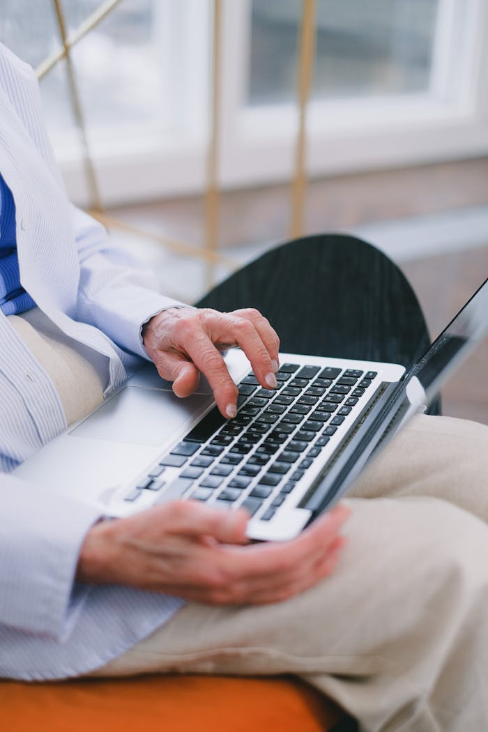 The Art of Drawing Readers In: Your attractive post title goes here Man in a formal shirt typing on a laptop, seated in a modern indoor space.